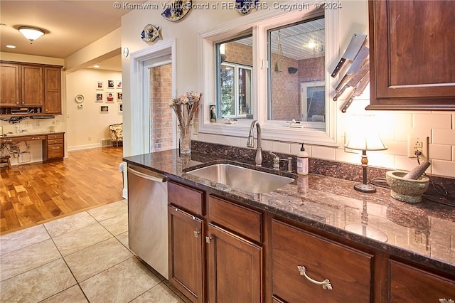 kitchen with backsplash, dark stone counters, dishwasher, light hardwood / wood-style floors, and sink