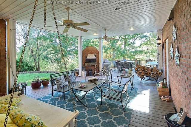 deck featuring ceiling fan and an outdoor stone fireplace