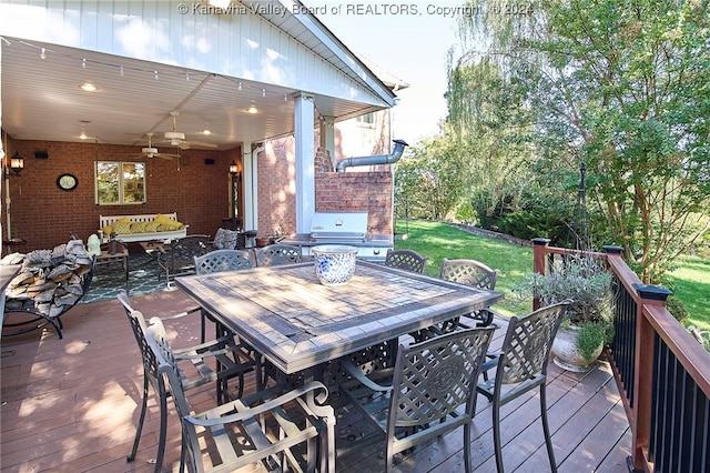 wooden deck with area for grilling, a lawn, and ceiling fan