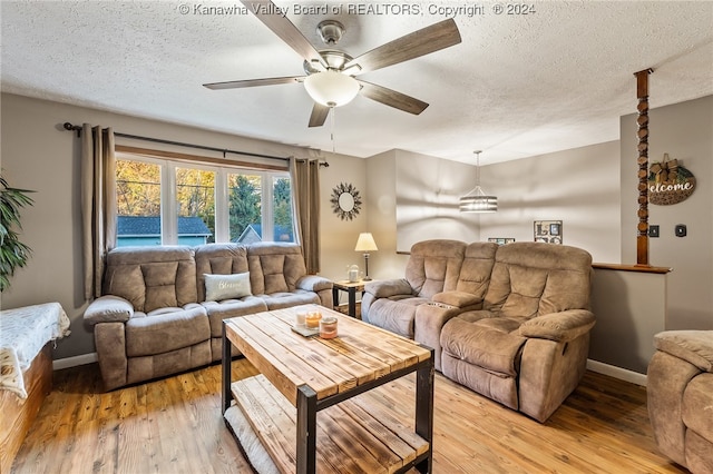 living room featuring a textured ceiling, light hardwood / wood-style floors, and ceiling fan