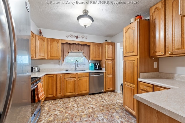 kitchen featuring a textured ceiling, stainless steel appliances, and sink