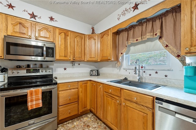 kitchen featuring a textured ceiling, appliances with stainless steel finishes, and sink