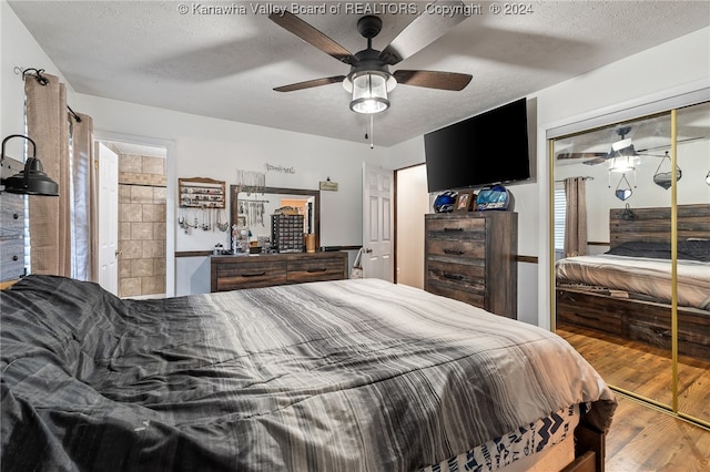 bedroom with a closet, hardwood / wood-style floors, ceiling fan, and a textured ceiling