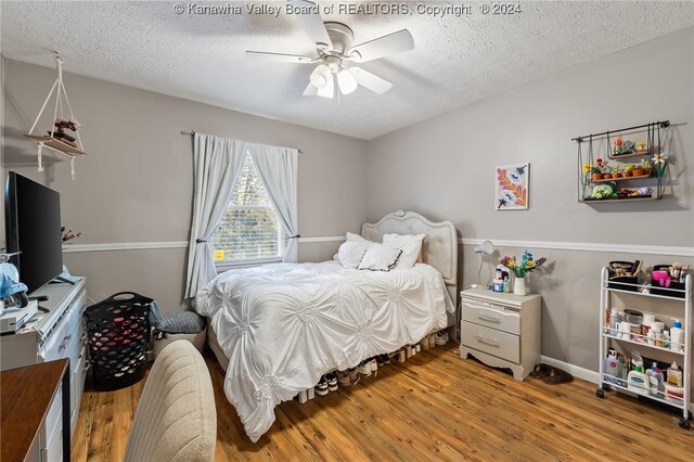 bedroom with hardwood / wood-style flooring, a textured ceiling, and ceiling fan