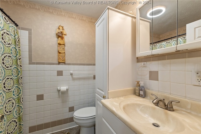 bathroom featuring tile walls, walk in shower, vanity, a textured ceiling, and toilet