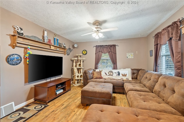 living room with ceiling fan, a textured ceiling, and light hardwood / wood-style floors