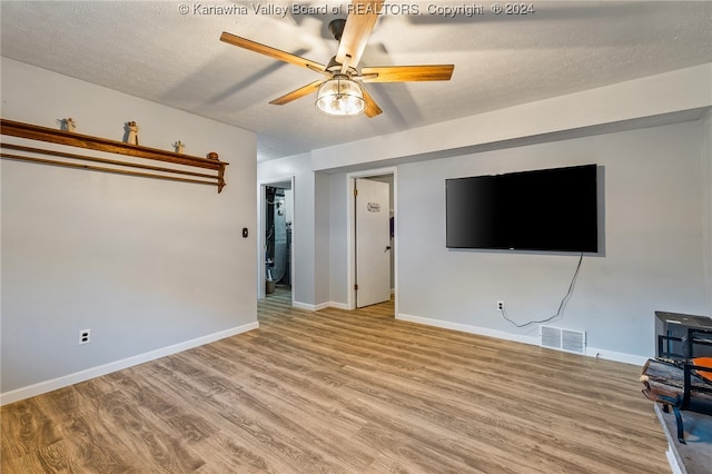 unfurnished living room with a textured ceiling, light hardwood / wood-style floors, and ceiling fan