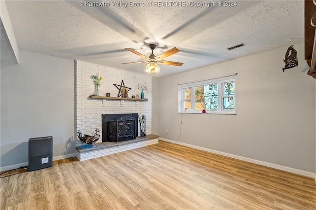 unfurnished living room featuring hardwood / wood-style floors, ceiling fan, a textured ceiling, and a fireplace