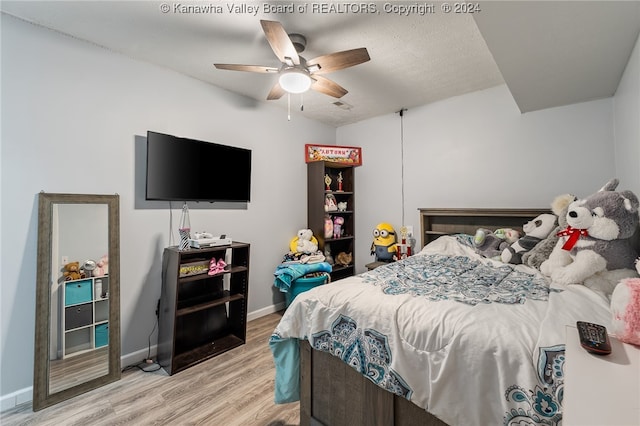 bedroom with hardwood / wood-style floors, ceiling fan, and a textured ceiling