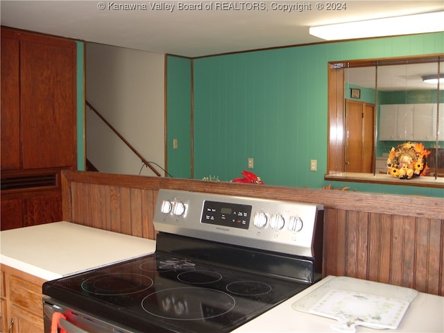 kitchen featuring electric stove and wood walls