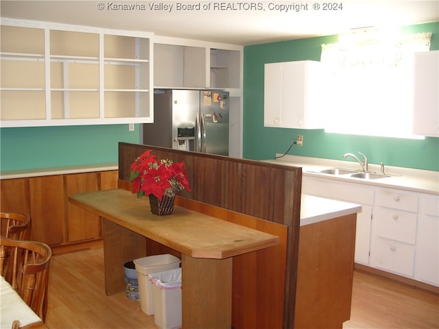 kitchen featuring sink, white cabinetry, stainless steel refrigerator with ice dispenser, and light hardwood / wood-style flooring