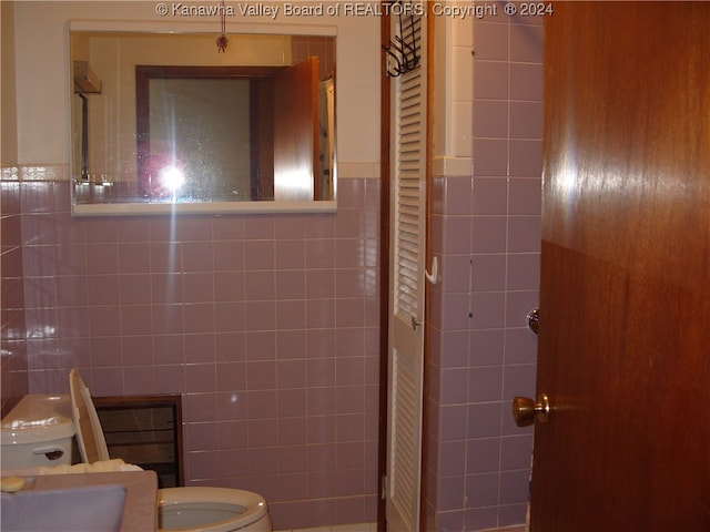 bathroom featuring toilet and tile walls