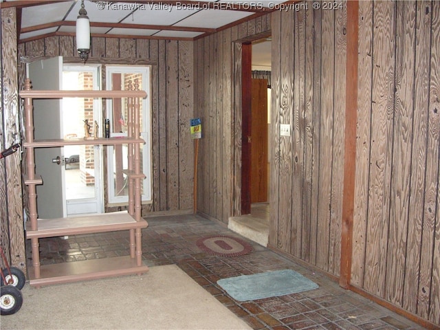 interior space featuring lofted ceiling and wood walls