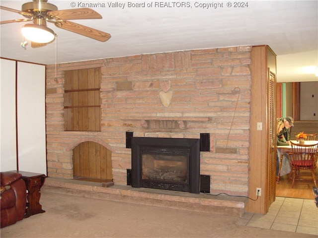 living room featuring built in features, a fireplace, light wood-type flooring, and ceiling fan