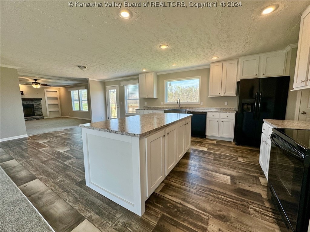 kitchen with black appliances, white cabinetry, a textured ceiling, and a kitchen island