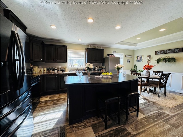 kitchen with a textured ceiling, a center island, dark hardwood / wood-style floors, and stainless steel refrigerator with ice dispenser