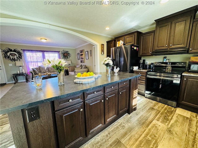 kitchen featuring appliances with stainless steel finishes, a center island, dark brown cabinetry, crown molding, and light hardwood / wood-style flooring