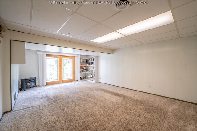 interior space featuring french doors, a wood stove, carpet floors, and a drop ceiling