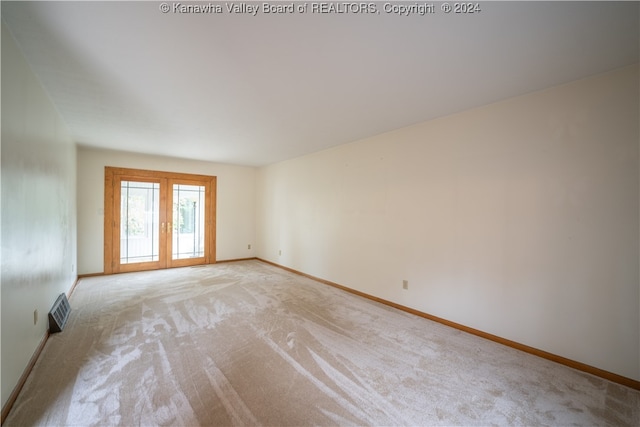 empty room featuring french doors and light carpet