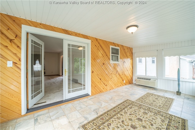 unfurnished sunroom featuring a wall mounted air conditioner and a healthy amount of sunlight