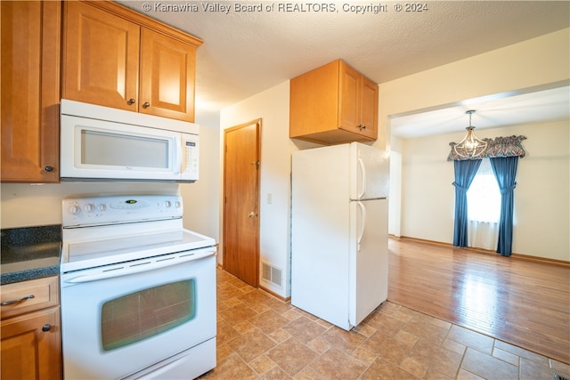 kitchen featuring decorative light fixtures, white appliances, a textured ceiling, and light hardwood / wood-style floors