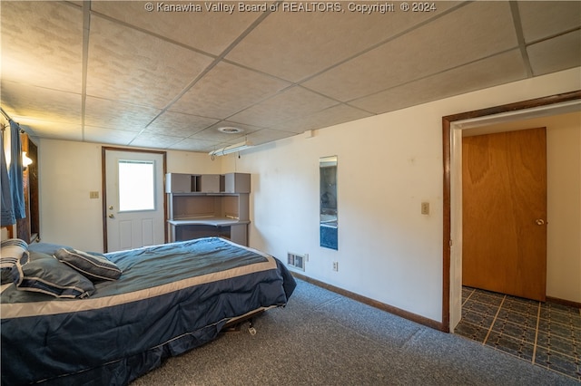 bedroom with dark colored carpet and a paneled ceiling