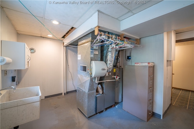 utility room featuring gas water heater, sink, and heating unit