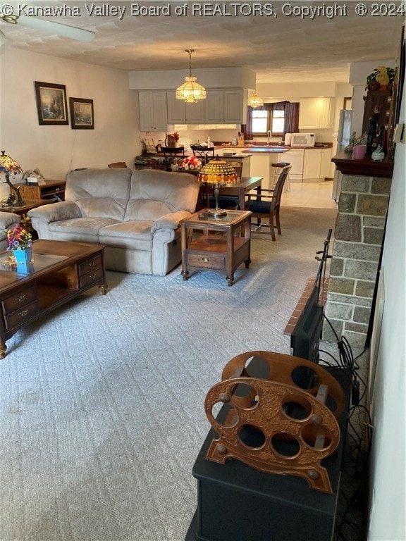 living room with a stone fireplace, light colored carpet, and sink