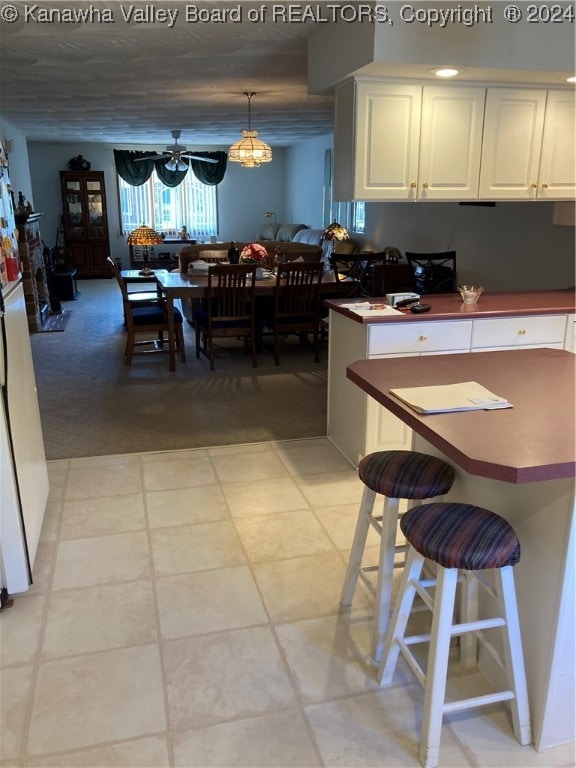 kitchen featuring hanging light fixtures, a breakfast bar area, light tile patterned floors, and white cabinets