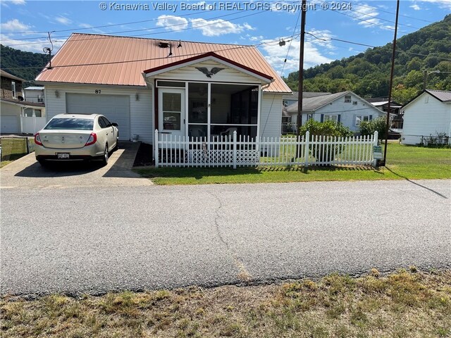 view of front of home featuring a garage, a sunroom, and a front yard