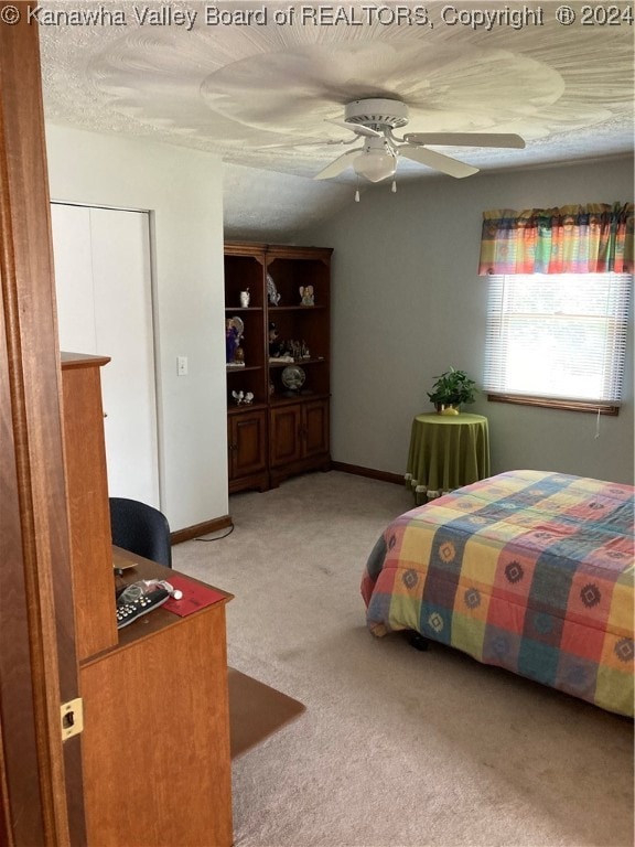 bedroom featuring ceiling fan, a textured ceiling, and light carpet