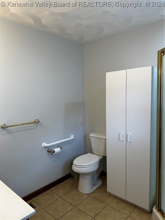 bathroom with tile patterned flooring, toilet, and a textured ceiling