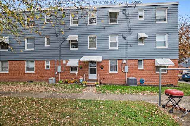 rear view of property with central air condition unit and a yard