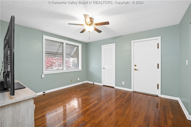 unfurnished living room featuring dark wood-type flooring, a textured ceiling, and ceiling fan