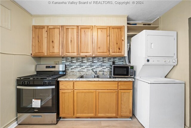 302 Kenna Dr, South Charleston, WV 25309 - kitchen with estacked washer and dryer, appliances with stainless steel finishes, tasteful backsplash, light wood-style floors, and light stone countertops