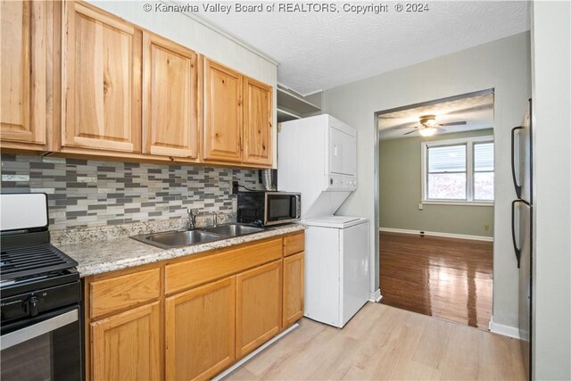 302 Kenna Dr, South Charleston, WV 25309 - kitchen featuring stacked washer / dryer, stainless steel range with gas stovetop, light wood-type flooring, tasteful backsplash, and a ceiling fan