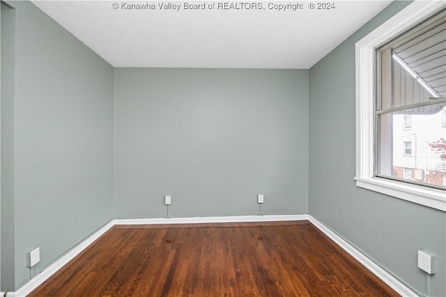 empty room with dark wood-type flooring and a textured ceiling