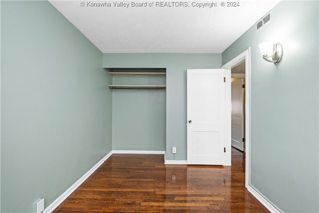 unfurnished bedroom featuring dark wood-type flooring and a closet