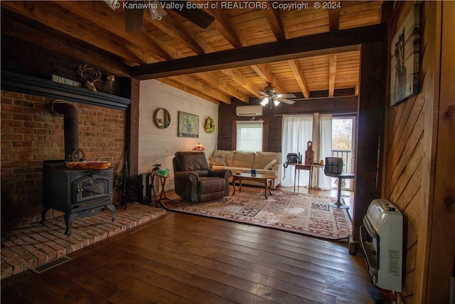 living room with dark wood-type flooring, a wood stove, wood walls, heating unit, and an AC wall unit