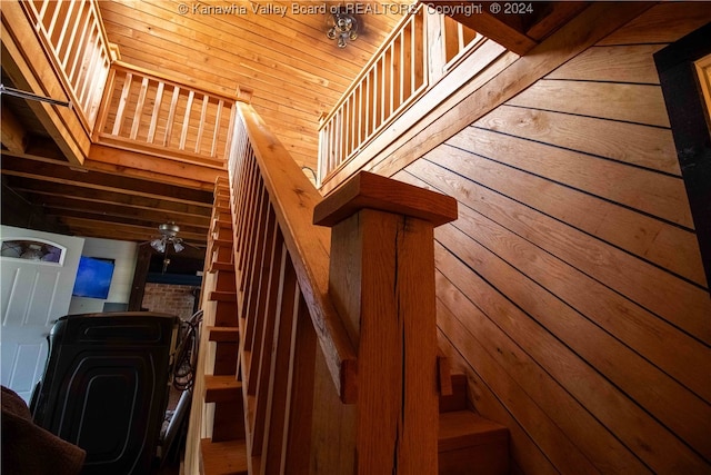 stairs featuring wooden walls, ceiling fan, and wood ceiling