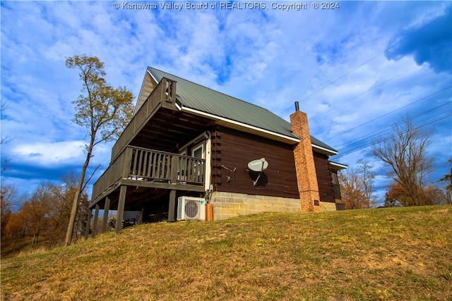 view of side of home with a wooden deck, a yard, and ac unit