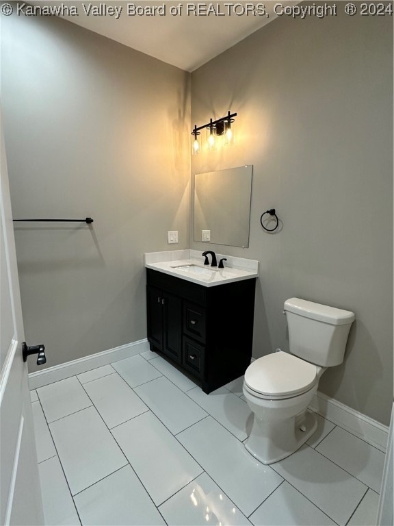 bathroom with toilet, vanity, and tile patterned floors