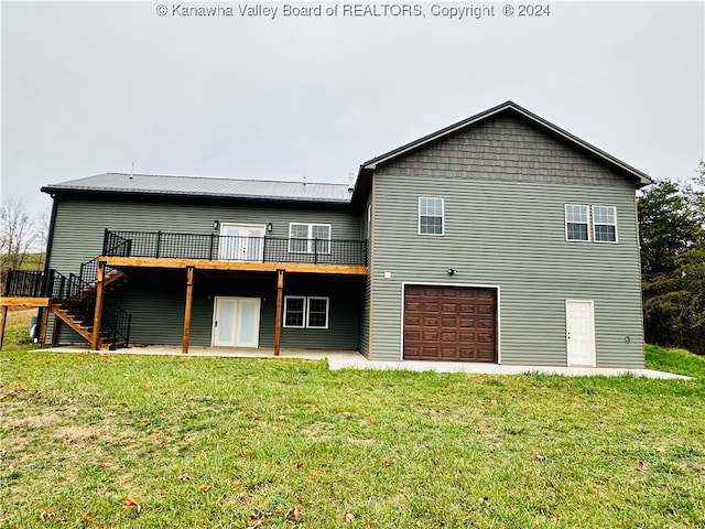 rear view of house featuring a garage, a wooden deck, and a lawn