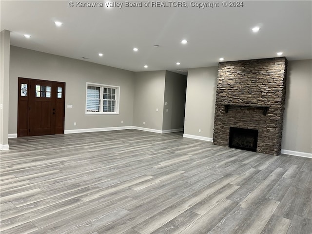 unfurnished living room featuring a stone fireplace and light wood-type flooring