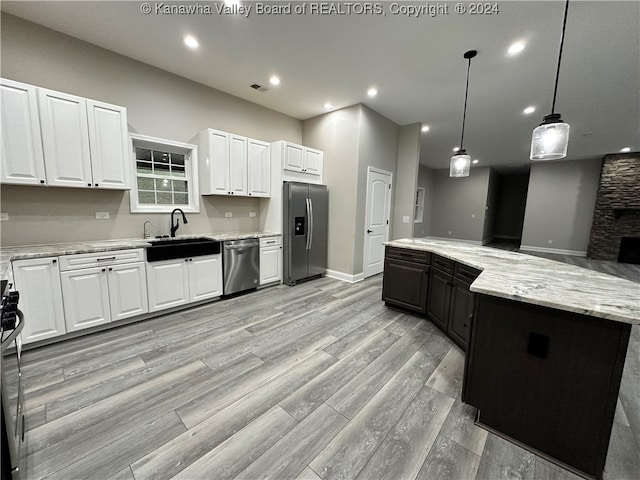 kitchen with stainless steel appliances, light hardwood / wood-style floors, decorative light fixtures, a center island, and white cabinets