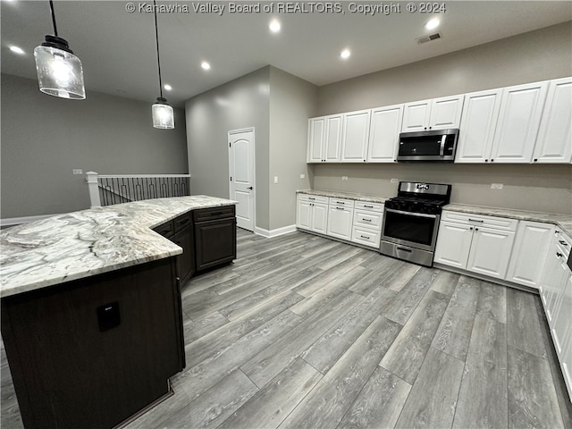 kitchen with light hardwood / wood-style flooring, a kitchen island, white cabinetry, appliances with stainless steel finishes, and decorative light fixtures