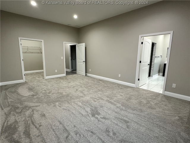 unfurnished bedroom featuring light carpet, a closet, and a walk in closet