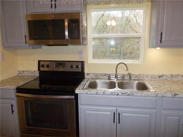 kitchen with a healthy amount of sunlight, stainless steel appliances, sink, and white cabinets