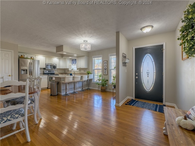 foyer with light hardwood / wood-style floors, a textured ceiling, and sink