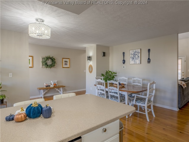 kitchen featuring a textured ceiling, hardwood / wood-style floors, and white cabinets